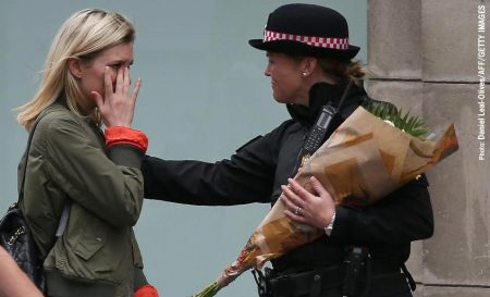 A woman reacts after asking a Police officer to lay flowers near London Bridge as a tribute to the victims of the attack.