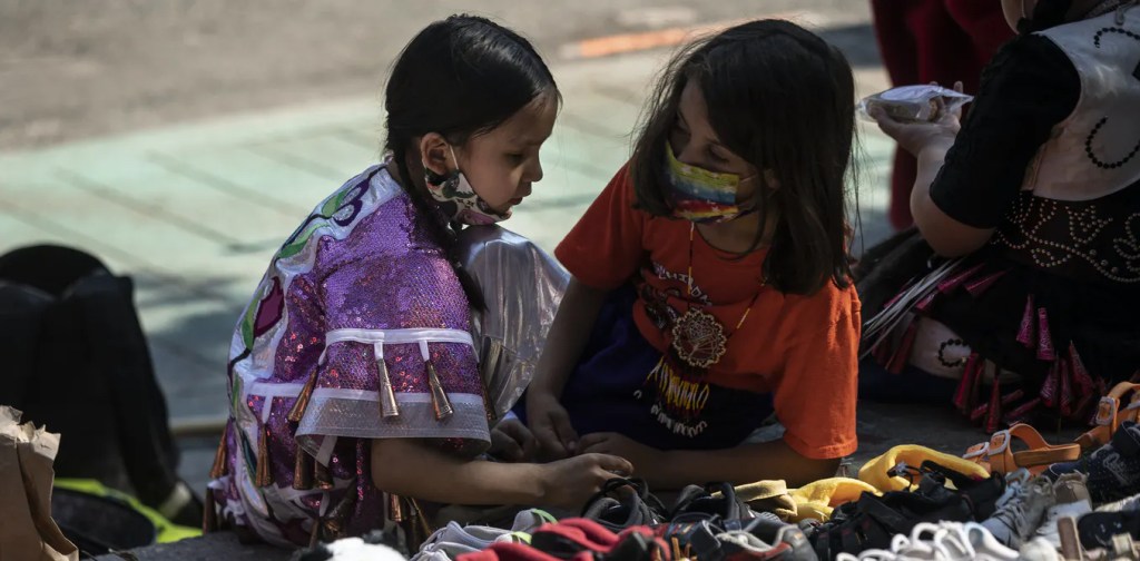 Indigenous Children in front of a statue of Egerton Ryerson